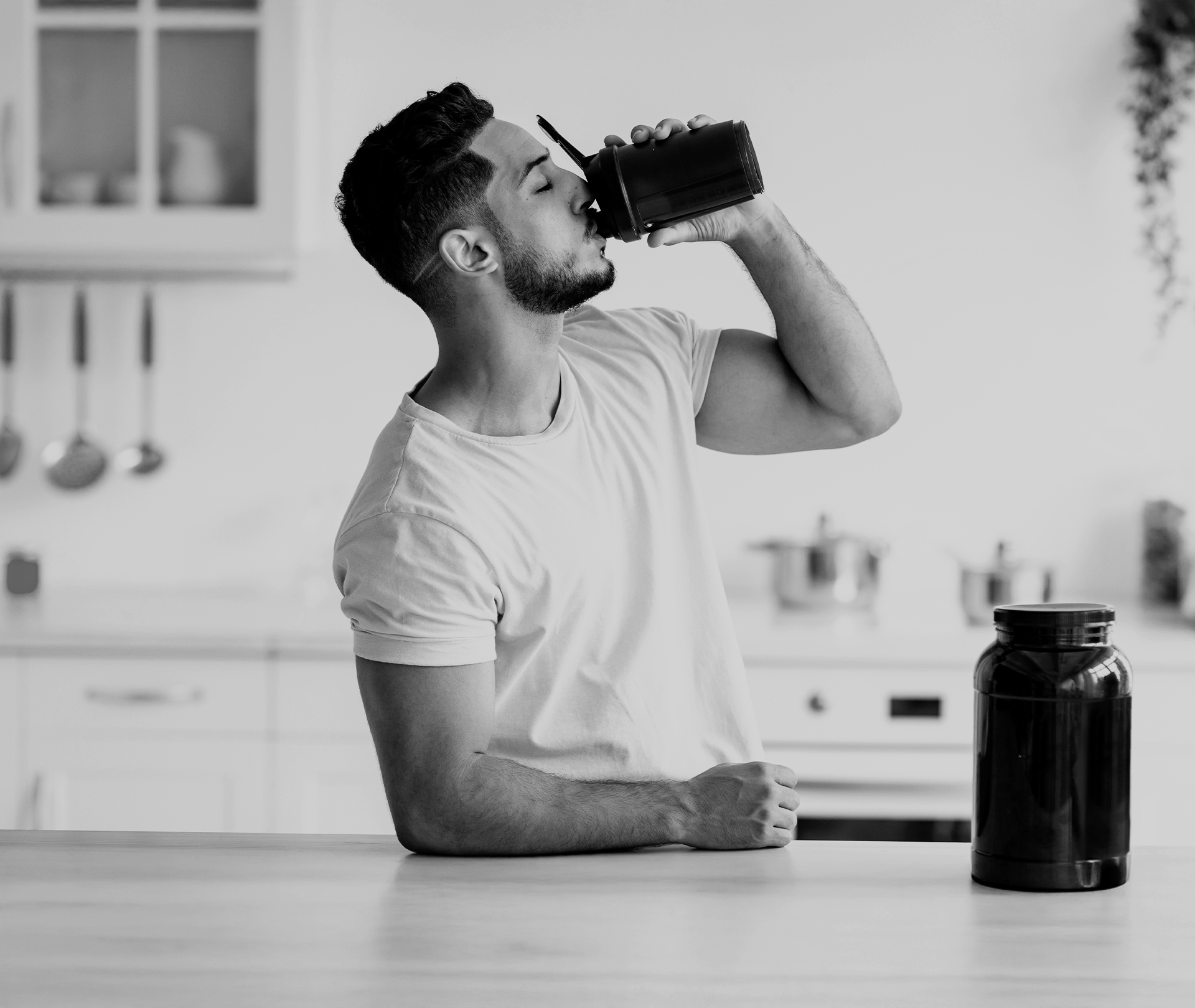 Mahlzeitenersatz: Shake und Riegel mit Protein Mann trinkt aus einem Shaker in der Küche.