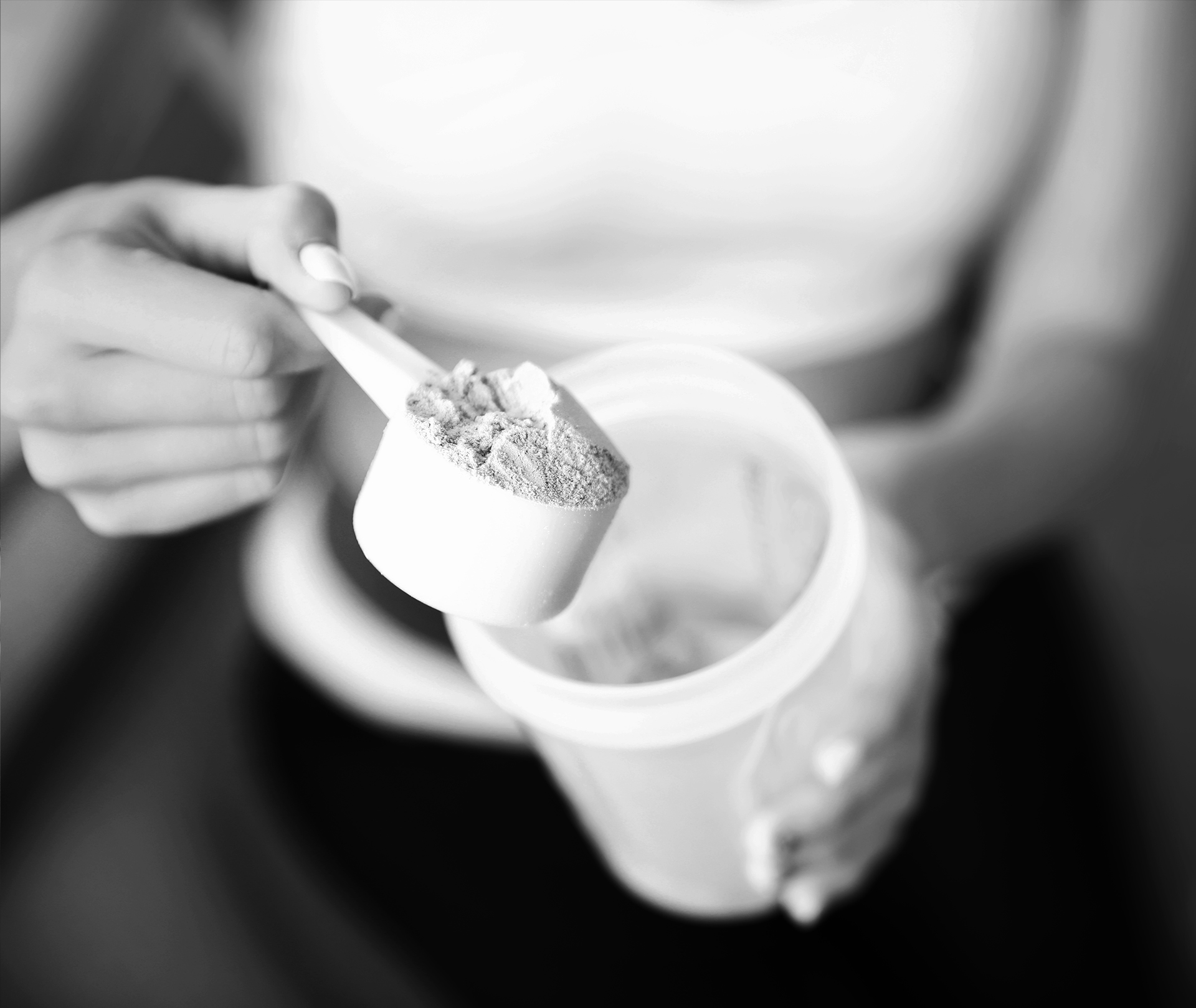 Proteinpulver für Frauen: Welche Proteine sind am besten? Frau macht einen Scoop Pulver in den Shaker
