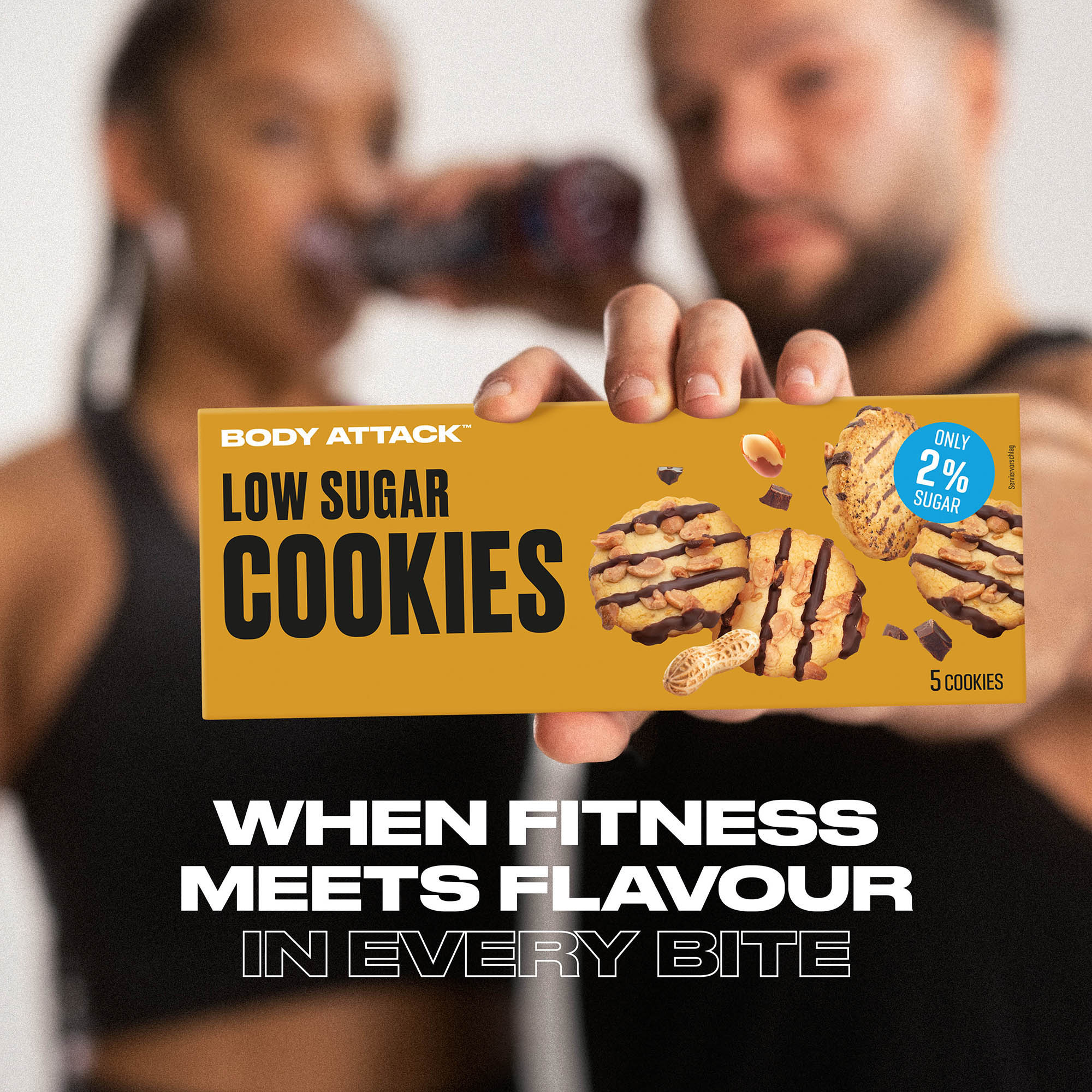 Eine Sportlerin und ein Sportler im Hintergrund halten eine Low Sugar Cookies Packung in den Vordergrund