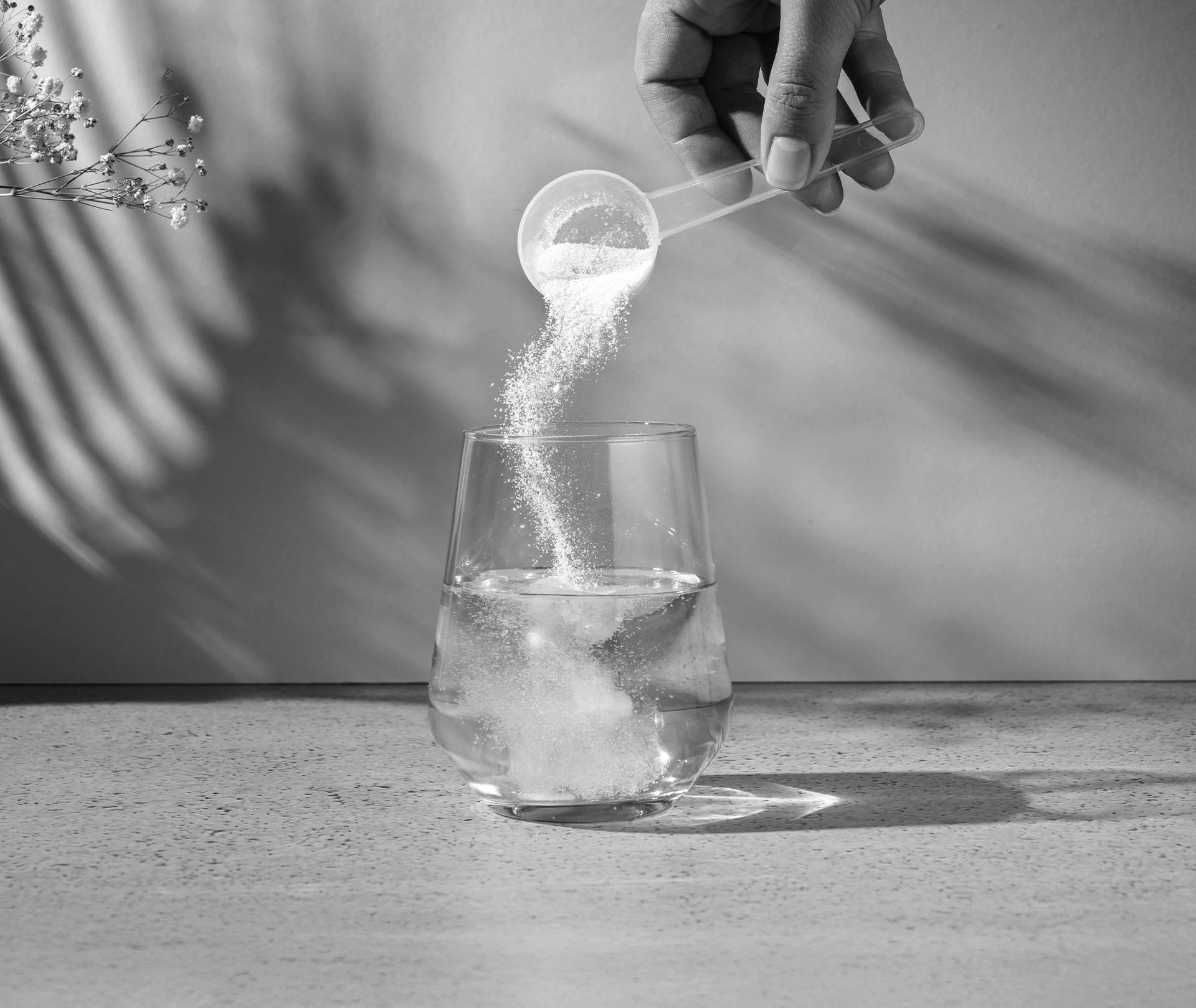 Kollagenmangel: Symptome für zu wenig Kollagen im Körper Wasserglas wird mit einem Scoop Pulver befüllt.